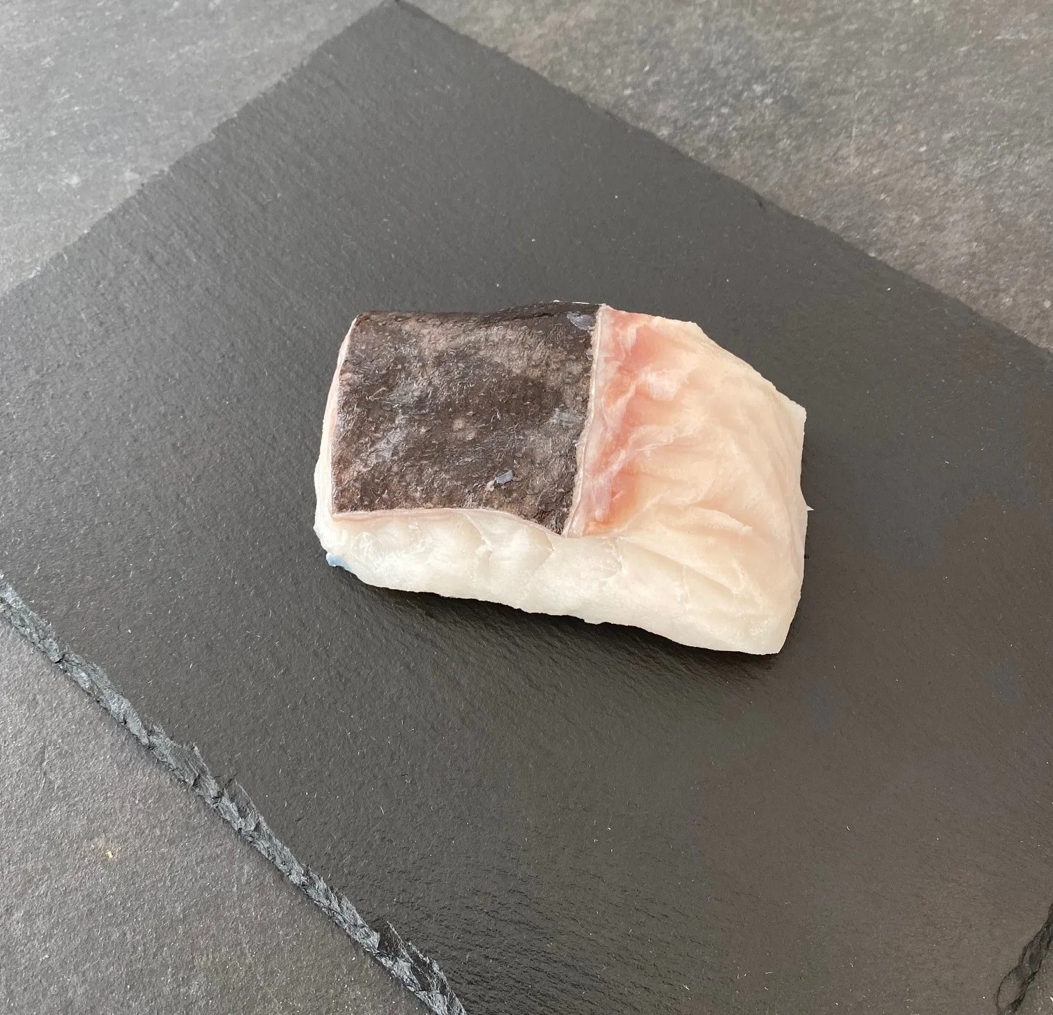 Bit av hälleflundra med skinn